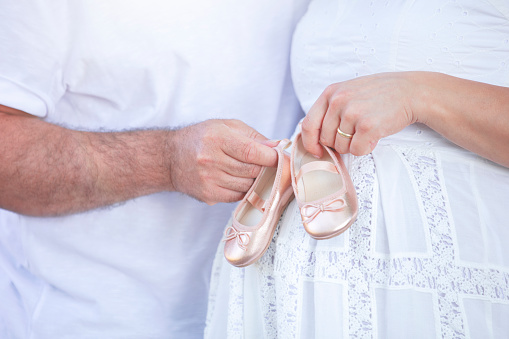 caucasian white ethnicity couple holding shoes of their soon-to-be-born baby at outdoor, love and happiness, new life,  Pregnancy, parenthood concept