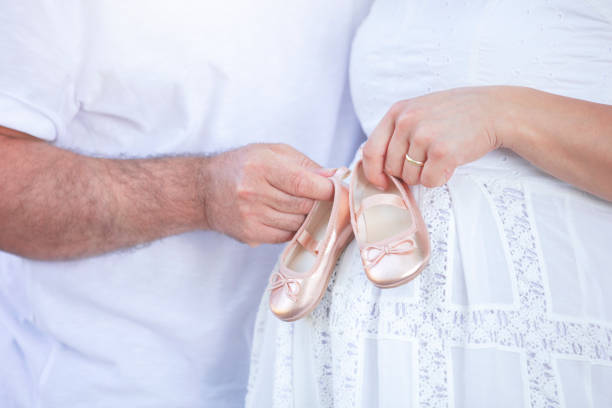 future parents holding a pair of unborn baby's little shoes - pair couple mid adult happiness imagens e fotografias de stock