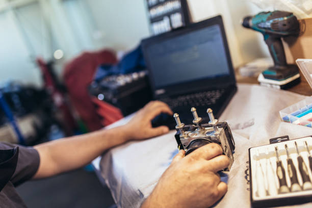 istock Professional car mechanic working in auto repair service using laptop. 1323925233