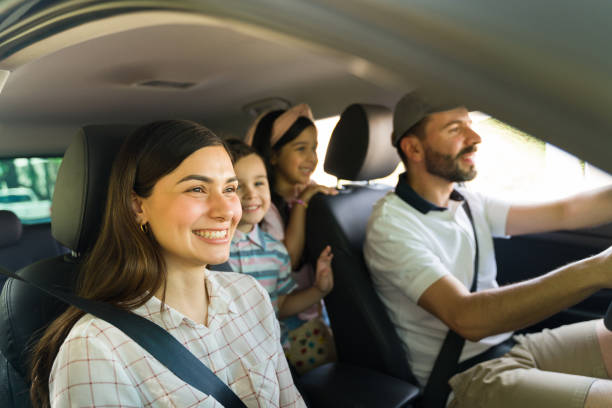 Mom, dad and children enjoying a car ride Excited to get to the beach! Beautiful hispanic family feeling happy while driving to a vacation spot with their little kids family in car stock pictures, royalty-free photos & images