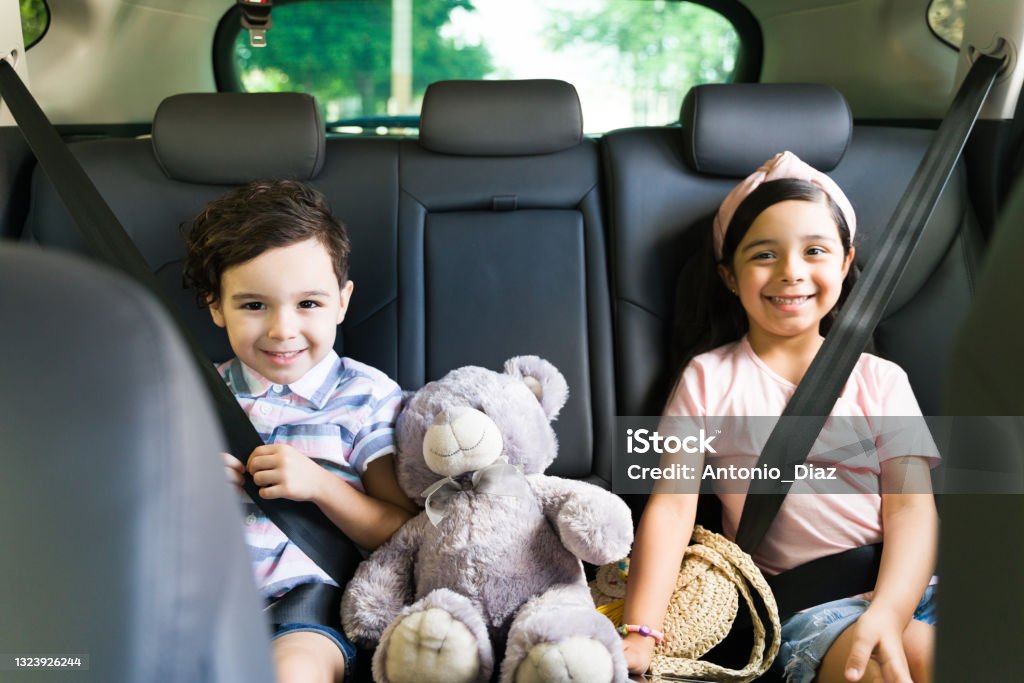 Happy siblings going on an exciting road trip Well-behaved kids sitting in the car. Portrait of an adorable little brother and sister smiling while waiting for their parents with their seat belt on Car Stock Photo