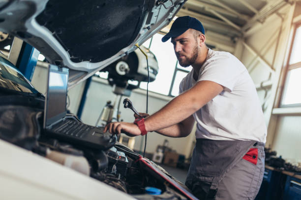 istock Professional car mechanic working in auto repair service using laptop. 1323928365