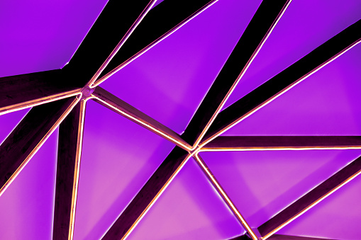 Glowing LED strip of abstract shape of triangles of various sizes on a purple neon background, front view.