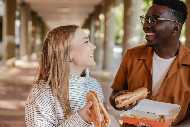 istock Young people are eating hot dog and walking 1323930672