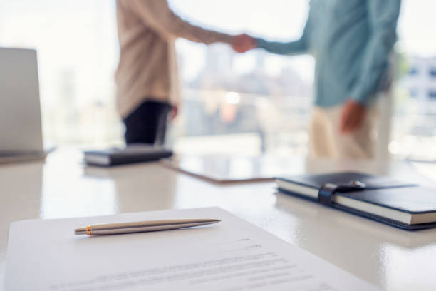 istock Two businessmen shaking hands with a contract 1323936751