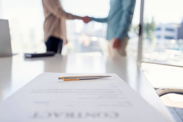 istock Two businessmen shaking hands with a contract. 1323936754