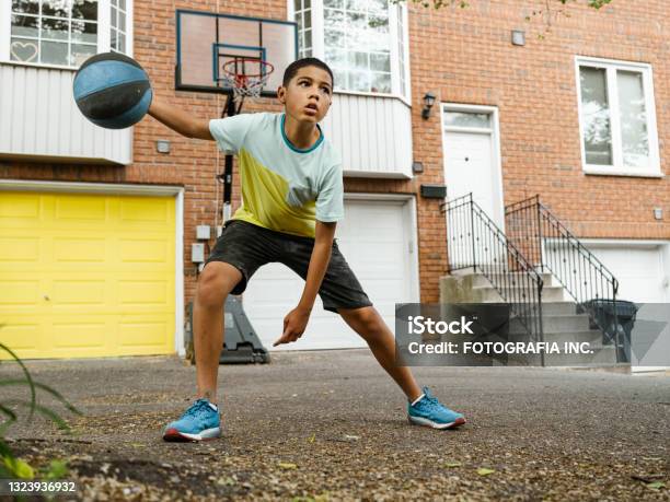 Mixed Race Boy Playing Basketball In The Alley Stock Photo - Download Image Now - Basketball - Sport, Basketball - Ball, Teenager