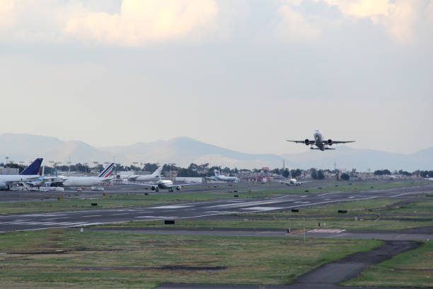 istock Airplane taking off or landing on runway with blue sky between clouds and mountains 1323939975