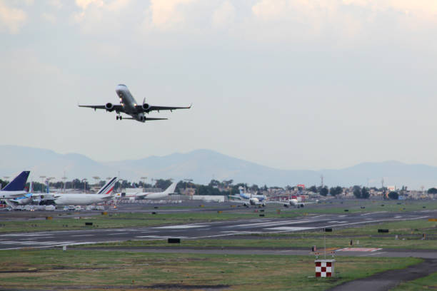 istock Airplane taking off or landing on runway with blue sky between clouds and mountains 1323939989