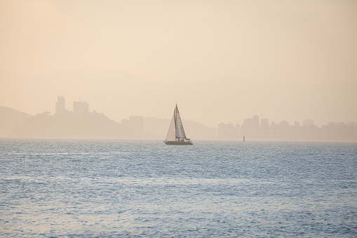 Sailboat sailing in the bay of Santos, Brazil, in a foggy and sunny day.