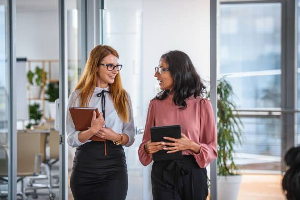 istock Friendly Businesswomen Talking as They Move Through Office 1323947833