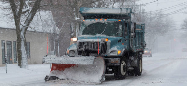 istock Blue snow plow with a red plow clearing main street during a snow storm 1323949716