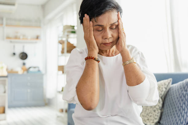An elderly Asian woman uses her hand to grasp the head. Old women have dizziness and headache due to stress. She has a congenital disease. The health concept of retirement stock photo