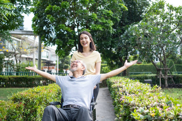 Asian happy Senior retired grandfather have fun outdoor at green park. Attractive girl daughter running and pushing elderly father raising arm on wheelchair with smile face, enjoy hearth care activity asiático feliz abuelo jubilado senior divertirse al aire libre en el parque verde. atractiva niña hija corriendo y empujando padre anciano levantando el brazo en silla de ruedas con cara de sonrisa, disfrutar de la actividad de cuidado del hogar