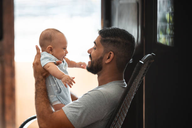 Father playing baby son rocking chair
