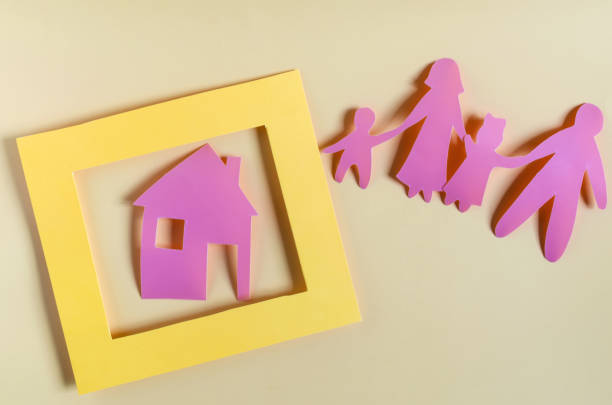 istock Bright red human figures and a house in a yellow frame on a light background. The concept of family and mortgage. Cardboard figures of adults and children close-up concept of a housing problem 1323961664