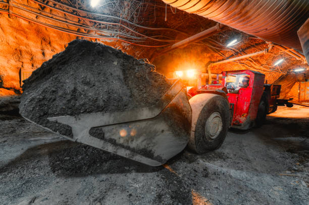 une machine de chargement souterraine transporte un seau plein de minerai. équipement spécial à profil bas pour les travaux souterrains - sous terre photos et images de collection