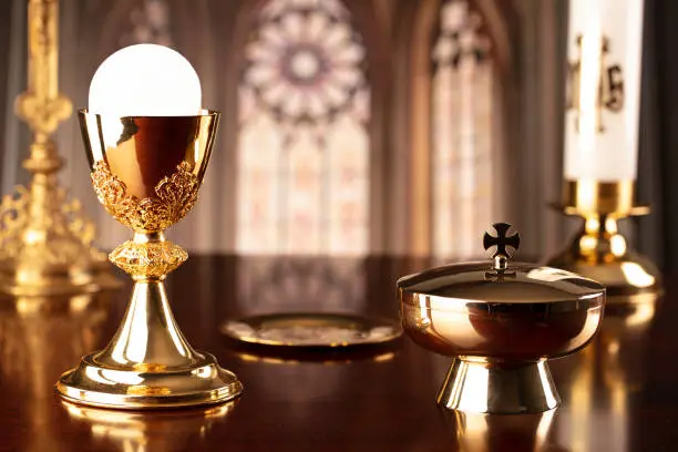 Crucifix, the Cross and Golden chalice and wafer on the altar in the church.