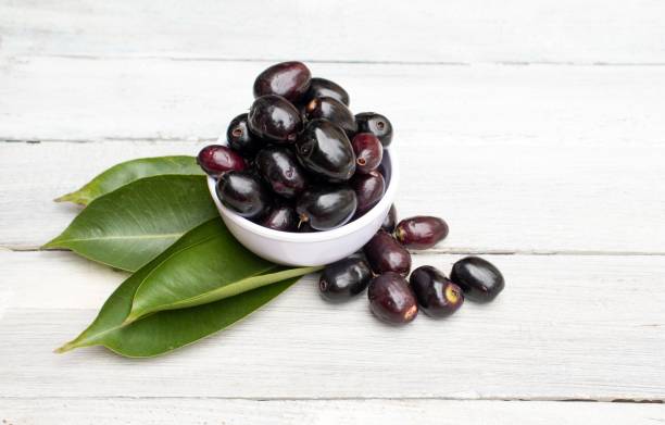 jamun ou ameixa preta em uma tigela com folhas isoladas em fundo de madeira branca com espaço de cópia, também conhecido como malabar plum ou jambolan - plum leaf fruit white - fotografias e filmes do acervo