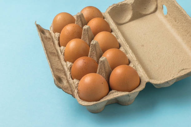 istock An open box of brown eggs on a blue background. 1323973636