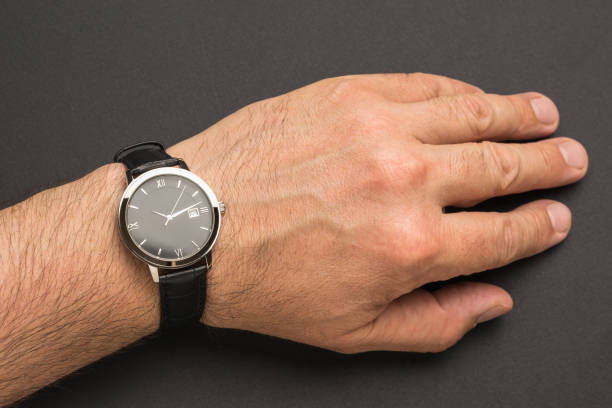 istock Men's hand with a classic wrist watch on a black background. 1323973638