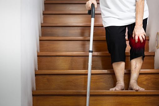 Mano de la anciana que sostiene su rodilla dolor con la mano y el bastón para apoyarse al caminar, la vejez tiene una lesión, dolorosa en la articulación y el hueso en la rodilla, síntomas de osteoartritis, artritis photo