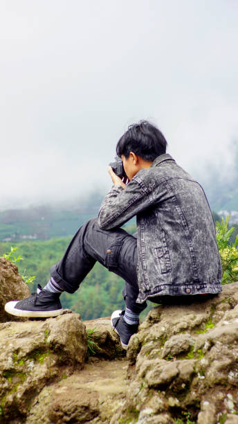 istock A boy takes a picture with a camera on a rock on a hill 1323973942