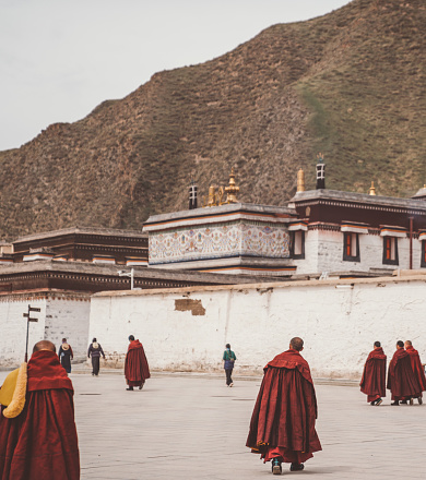 Xiahe, Tibet - June 1st 2021: Tibetan Buddhist monks walking at Labrang monastery. Labrang monastery is one of the most important and largest monasteries to Tibetan Buddhism. Labrang monastery is free and open to public.