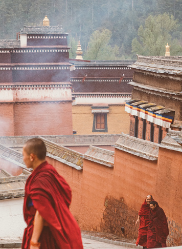 Xiahe, Tibet - June 1st 2021: Tibetan Buddhist monks walking at Labrang monastery. Labrang monastery is one of the most important and largest monasteries to Tibetan Buddhism. Labrang monastery is free and open to public.