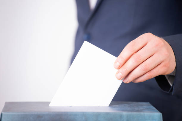 istock Voter Putting Ballot Into Voting box. 1323975858