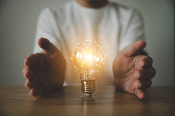 istock Hand holding light bulb on wood table. Concept of inspiration creative idea thinking and future technology innovation 1323976683
