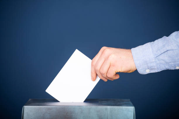istock Voter Putting Ballot Into Voting box. 1323976827