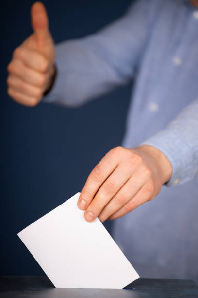 istock Voter Putting Ballot Into Voting box. 1323977589