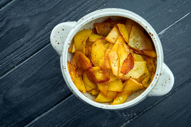 istock Appetizing side dish - fried potatoes with onions served in a white bowl on a dark background. 1323977908