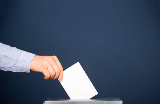 istock Voter Putting Ballot Into Voting box. 1323979583