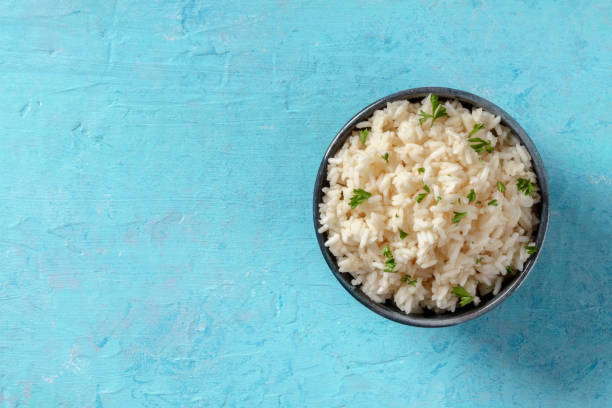 istock Boiled rice with parsley, shot from above on a blue background 1323979853