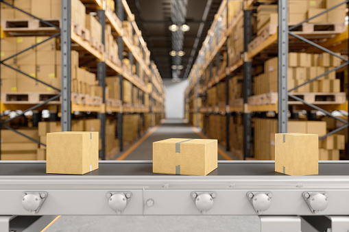 Cardboard Boxes Moving On Conveyor Belt In The Warehouse With Blurred Background.