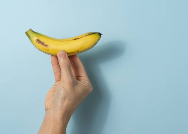 istock Hand a man holds banana with a copy space. 1323986075