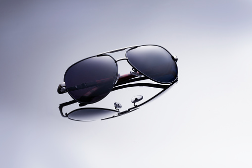 Modern fashionable, unisex sunglasses on mirror background. Perfect gradient reflection.