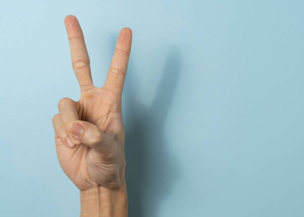 istock Hand a man show peace sign on blue background with a copy space. 1323986315