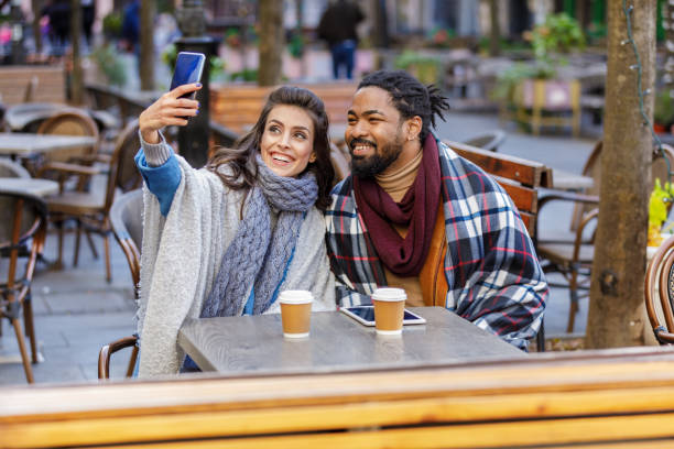 istock A Young Multi-Ethnic Couple is Spending a Wonderful Evening Together, Having a Lovely Communication and Sharing a Fresh Drink, and Taking Selfie Photos with Mobile Phone. 1323987135