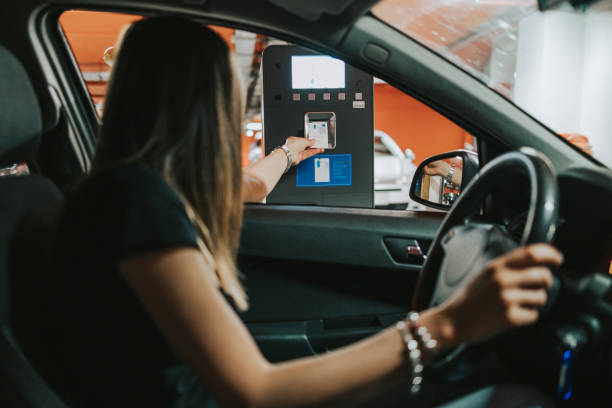 Just out of reach Young female driver using automated parking service to enter into huge underground garage. motor living stock pictures, royalty-free photos & images