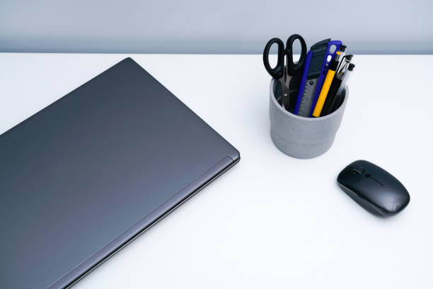 istock Laptop and pen holder on white desktop 1323988079
