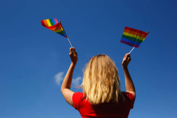 istock girl with lgbt flags behind her back against a bright blue sky 1323988319