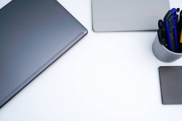 istock Laptop and pen holder on white desktop 1323988378