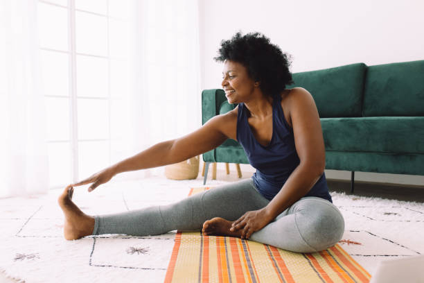 reife frau beim stretching-training zu hause - nur frauen über 40 stock-fotos und bilder