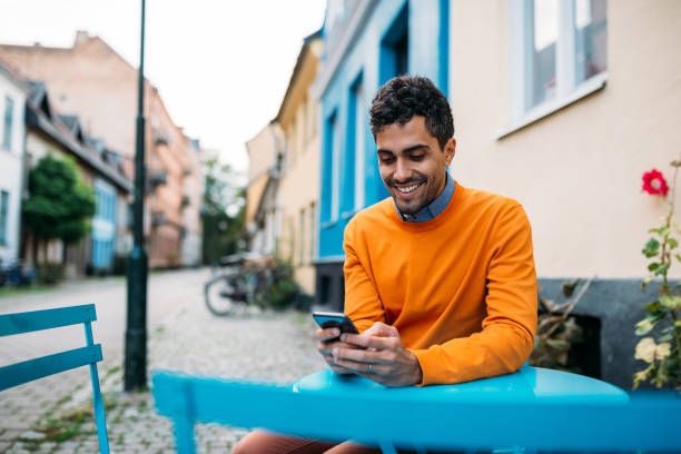 istock Brazilian man using mobile phone in cafe and smiling 1323990404