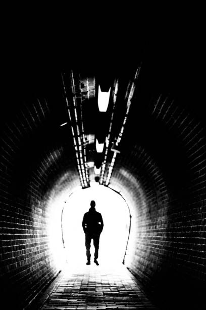 istock Man goes through a tunnel into the light 1323993848