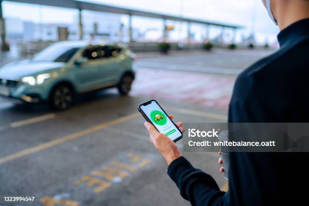 Chic Young Asian Man Using Mobile App Device On Smartphone To Order A Taxi Pick Up Service By The Urban Road In Downtown City Street Speedy And Trustworthy Service Carsharing And Business On The Go Themes Stock Photo - Download Image Now