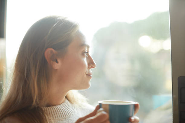 istock A beautiful woman drinking coffee and relaxing by the window. 1323997522